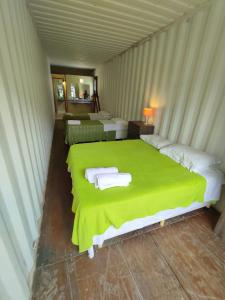 um quarto com uma cama verde com toalhas em Container Eco Suítes em Cabo Frio