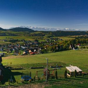 a small town in a green field with mountains in the background at Słoneczny Domek in Grywałd