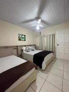 a bedroom with two beds and a ceiling fan at Pousada Recanto da Ana Alice in Abraão