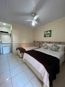 a bedroom with two beds and a ceiling fan at Pousada Recanto da Ana Alice in Abraão