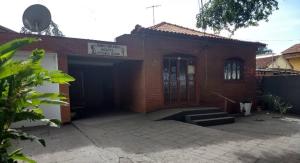 um edifício de tijolos vermelhos com uma garagem e uma porta em Pousada Recanto Alaketu Hospedagens em Campo Grande