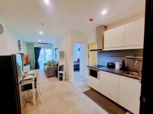 a kitchen with white cabinets and a living room at Patong Coco Apartment in Patong Beach