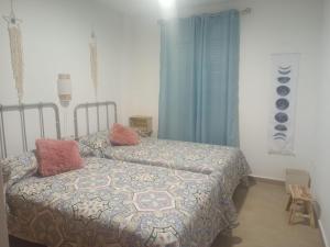 a bedroom with two beds and blue curtains at El Barro Colorao in Segura de León