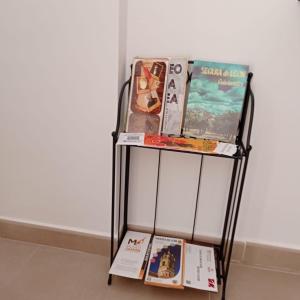 a metal shelf with books on it next to a wall at El Barro Colorao in Segura de León