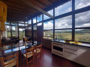 uma cozinha com mesa, cadeiras e janelas em Chalés da Serra Catarinense em Bom Jardim da Serra