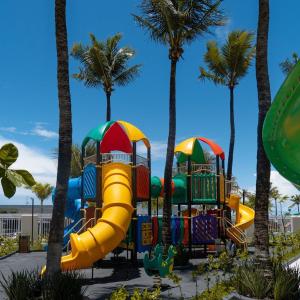 a colorful playground with palm trees in the background at Salinas Premium Resort in Salinópolis