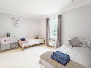 a white bedroom with two beds and a window at The White House - Bordon in Bordon