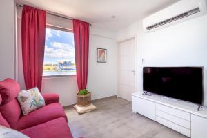 a living room with a red couch and a flat screen tv at World Heritage Apartments in Willemstad
