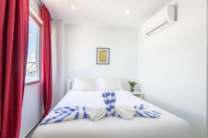 a bedroom with a white bed with red curtains at World Heritage Apartments in Willemstad