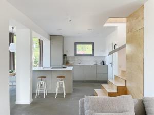 a kitchen and living room with white cabinets and stools at Bieleniówka in Nakielno