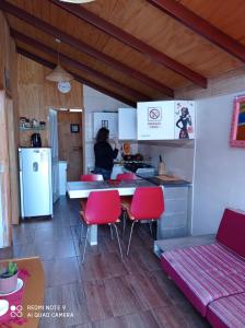 une femme debout dans une cuisine avec des chaises rouges dans l'établissement Las 3 Golondrinas, à El Quisco