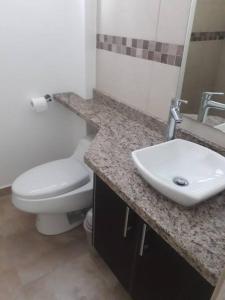 y baño con aseo blanco y lavamanos. en Edif. Deymar - Departamento frente al mar 9no piso, en Tonsupa