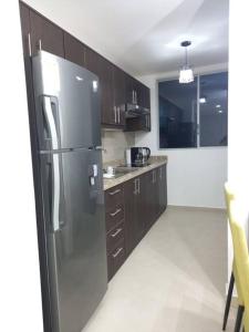 a kitchen with a stainless steel refrigerator and wooden cabinets at Edif. Deymar - Departamento frente al mar 9no piso in Tonsupa