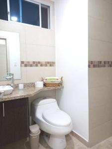 a bathroom with a white toilet and a sink at Edif. Deymar - Departamento frente al mar 9no piso in Tonsupa