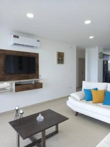 ein Wohnzimmer mit einem weißen Sofa und einem Tisch in der Unterkunft Edif. Deymar - Departamento frente al mar 9no piso in Tonsupa
