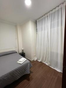 a bedroom with a bed and a window with white curtains at MARIÑIGUEZ APARTAMENT. in Jerez de la Frontera