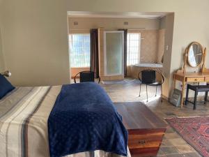 a bedroom with a bed and a desk and a piano at HEELTEVREDE Self-Catering farmhouse in Bloemfontein