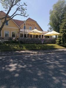 ein Gebäude mit Sonnenschirmen an der Straßenseite in der Unterkunft Centrum Étterem és Panzió in Őriszentpéter