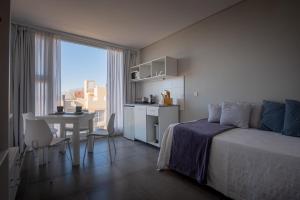 a bedroom with a bed and a kitchen and a table at Hotel Valeria Apart & Hotel Spa in Valeria del Mar