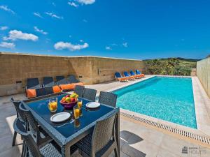 a patio with a table and chairs next to a swimming pool at The Arches Holiday Home in Kerċem