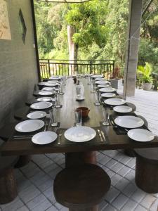 un lungo tavolo in legno con piatti bianchi di Dolagawa a Deniyaya