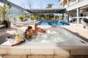 un hombre y una mujer sentados en un jacuzzi en Hotel Valeria Apart & Hotel Spa en Valeria del Mar