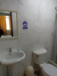 ein Badezimmer mit einem Waschbecken, einem WC und einem Spiegel in der Unterkunft HOTEL ALFONSO UGARTE in Chiclayo