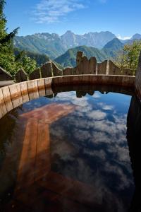 un puente sobre un estanque con montañas al fondo en Holiday chalet "Alpine dreams" en Solčava