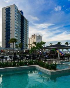 a swimming pool with tables and chairs and buildings at Salinas Exclusive Resort in Salinópolis