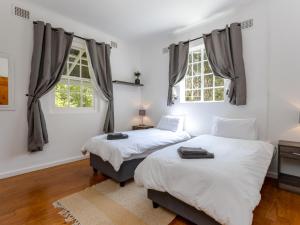 two beds in a room with two windows at Jonkershoek Valley Cottage in Stellenbosch