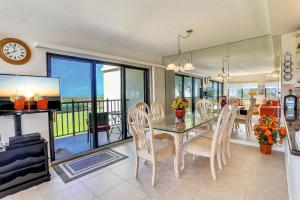 a dining room with a table and chairs and a television at Land's End 10-201 Beach Front - Premier in St Pete Beach