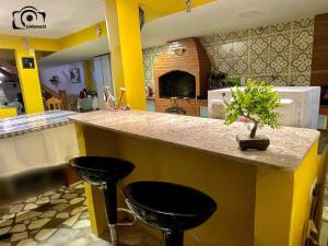 a kitchen with a counter with two black stools at Pousada Toca dos Coelhos in Arraial do Cabo