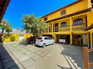 a car parked in a parking lot in front of a yellow building at Pousada Toca dos Coelhos in Arraial do Cabo