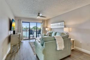 a living room with a couch and a sliding glass door at Land's End 4-202 Bay Front - Premier in St. Pete Beach
