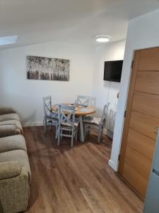 sala de estar con mesa, sillas y sofá en Town Centre Apartment, en Leek