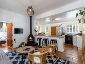 Jonkershoek Valley Cottage في ستيلينبوش: مطبخ وغرفة معيشة مع طاولة وكراسي