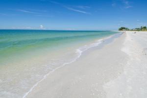 a white beach with people walking on the water at Land's End 5-204 Gulf-Bay Front - Premier in St. Pete Beach