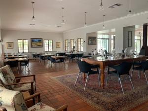 a dining room with tables and chairs and windows at Otjibamba Lodge in Otjiwarongo