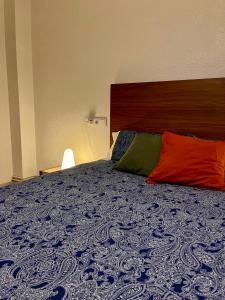 Una cama con dos almohadas de colores encima. en Piso con encanto, en Cehegín