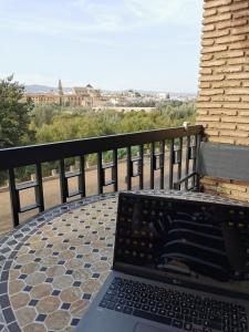 Las mejores vistas de Cordoba con parking privado gratuito في قرطبة: يوجد جهاز كمبيوتر محمول على طاولة في الشرفة