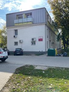 a large white building with cars parked in a parking lot at Stílusos lakás ingyenes parkolással in Debrecen