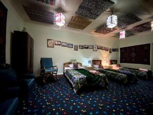 una camera d'albergo con due letti e una sedia di Barlos - уютная, семейная атмосфера a Bukhara