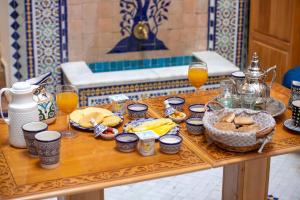 una mesa con alimentos para el desayuno y vasos de zumo de naranja en Dar Kenz Fes, en Fez