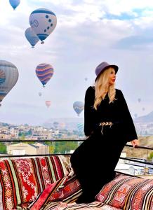 a woman in a black dress and a hat and hot air balloons at Seven Stone Hotel in Göreme