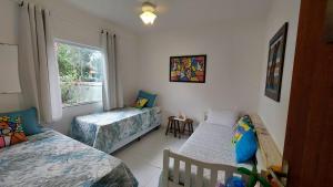um quarto com 2 camas e uma janela em Casa Azul, Long Beach Unamar Cabo Frio em Tamoios