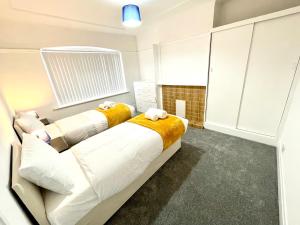 a room with a large white bed with yellow blanket at Lotus Home Wallasey in Wallasey