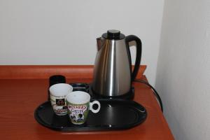 a coffee pot and two coffee mugs on a tray at Hotel De Ploeg in Diepenbeek