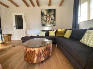 a living room with a couch with a tree stump coffee table at BERGLAGE - Das UrlaubZuhause - Ferienhäuser in Braunlage