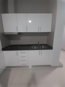 a white kitchen with a sink and white cabinets at Apartamentos Morabeza in Mindelo