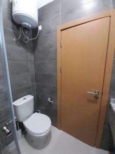 a bathroom with a toilet and a brown door at Apartamentos Morabeza in Mindelo